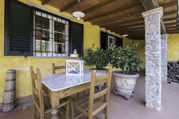 A wooden table with chairs, a lantern, and potted plants in an outdoor patio area. - Casa Fortunato, pool and sauna (Camaiore)