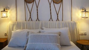 A bed with white bedding and a woven headboard. There are two wall-mounted lamps on either side of the bed. - Porto Thassos (Thasos)