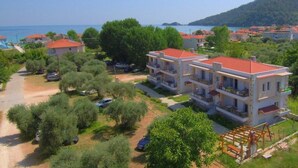 A coastal residential area with multi-story buildings, a clear view of the sea, and a hilly backdrop. - Porto Thassos (Thasos)