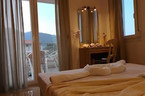 Habitación de hotel con cama, escritorio con espejo y vistas al exterior.