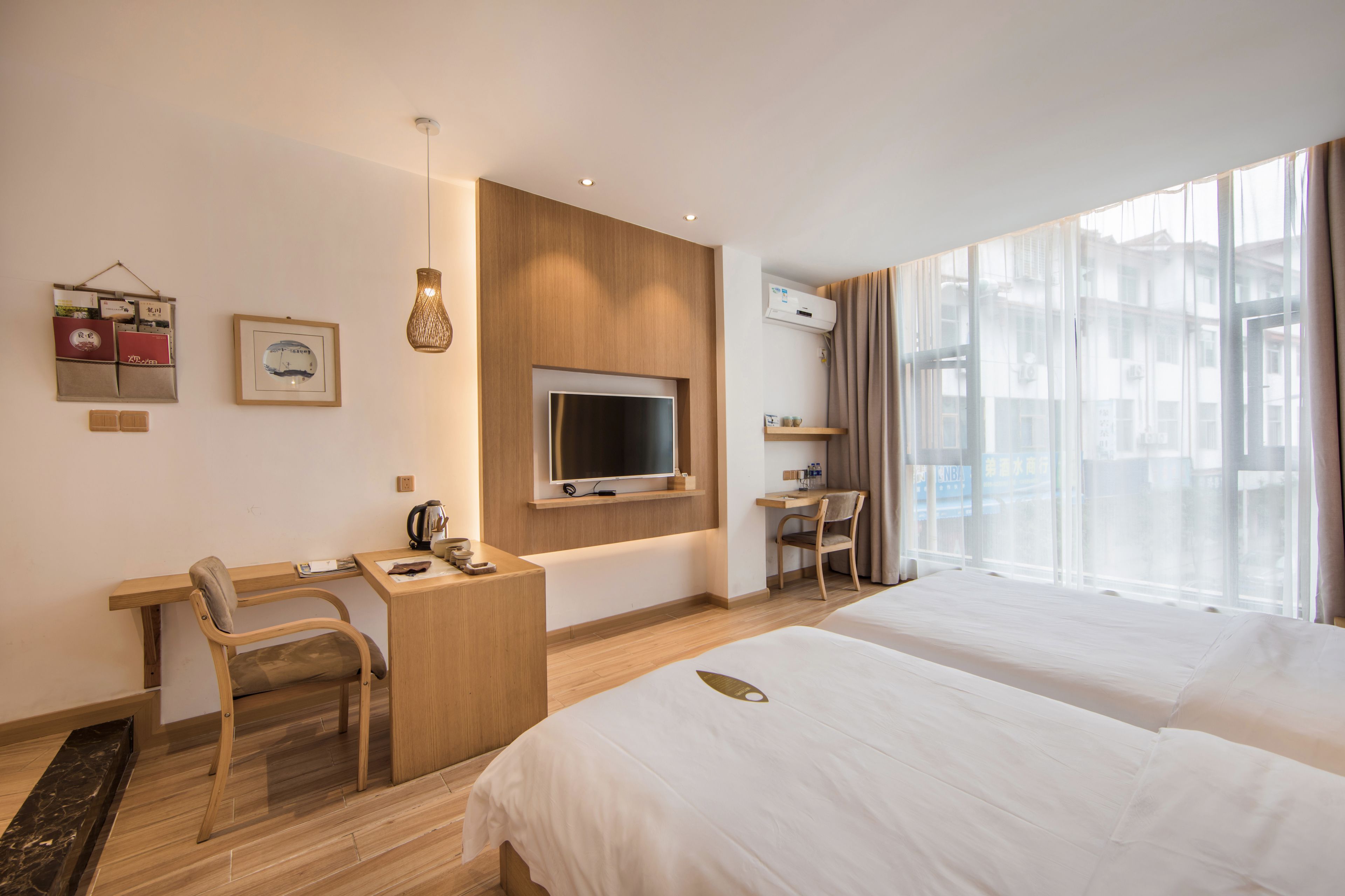 Camera d'albergo con letto, scrivania, sedia, televisore e ampie finestre.