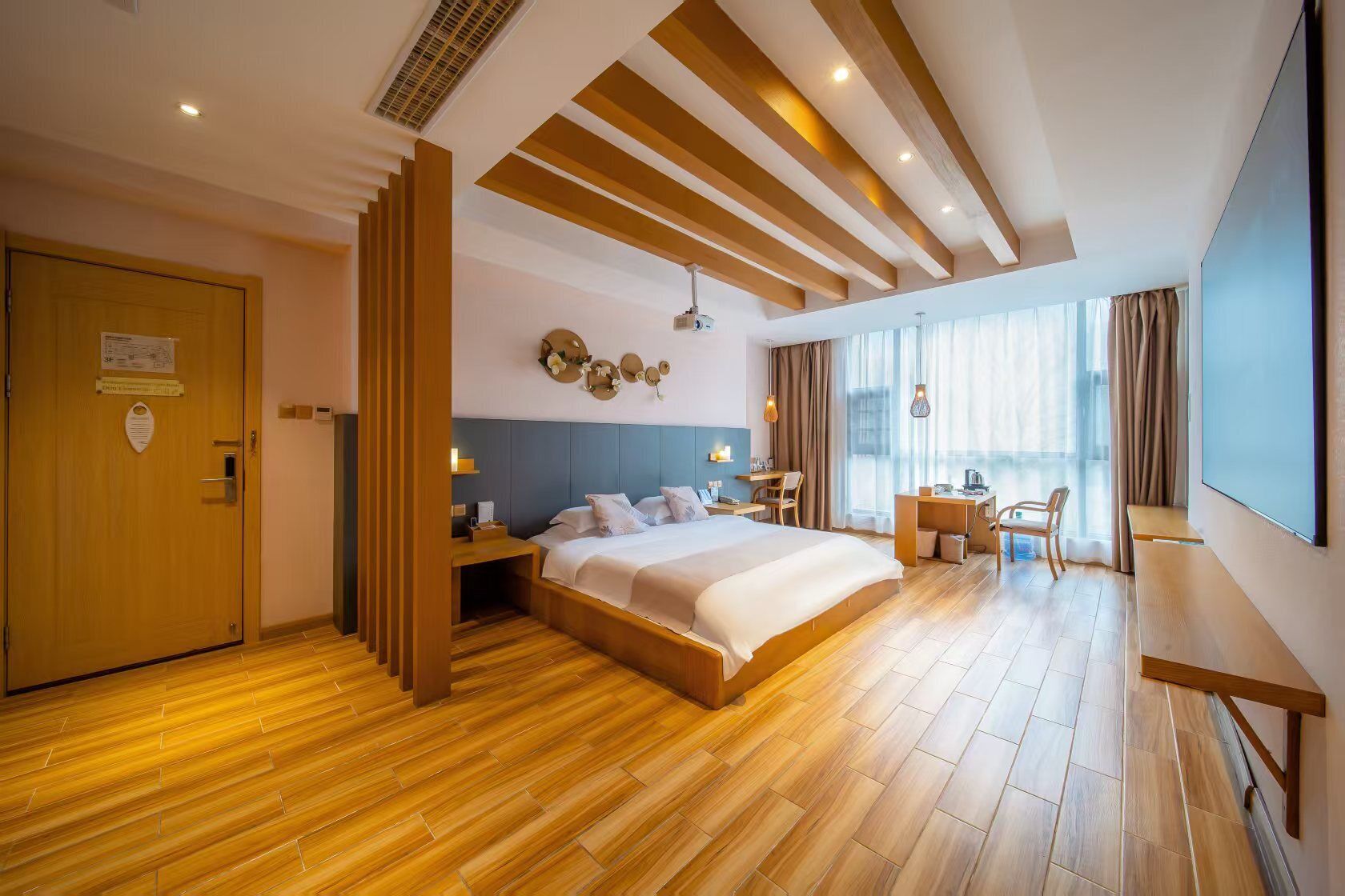 Una camera d'albergo moderna con un letto grande, una scrivania e un'ampia finestra.