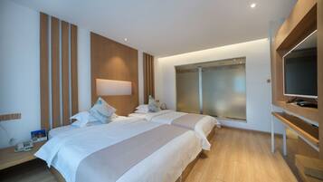 A modern hotel room with two beds, a TV, and a large window.