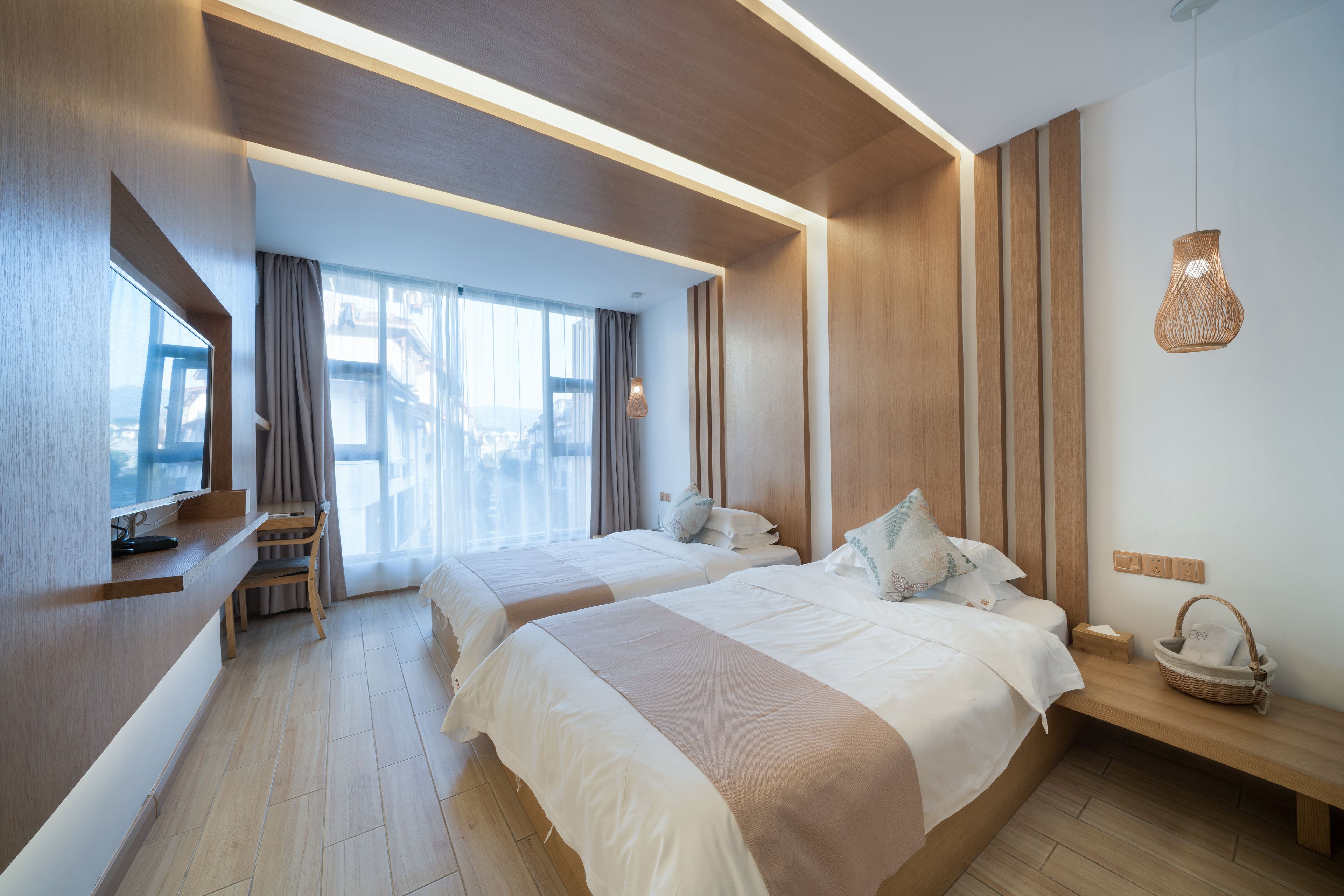 A modern hotel room with two beds, a desk, and a large window.