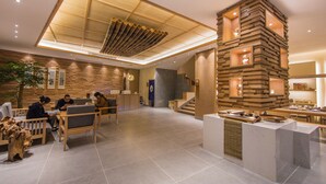 A modern lobby with a wooden reception desk, seating area, and a staircase leading to upper floors. - Wuyishan Ancient Street No.3 Tea Inn (Nanping)