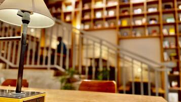 A lamp on a wooden table with a bookshelf in the background.