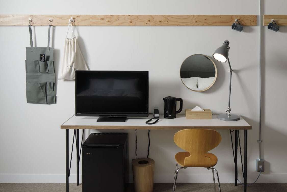 A minimalist office setup with a desk, computer, lamp, and storage solutions.
