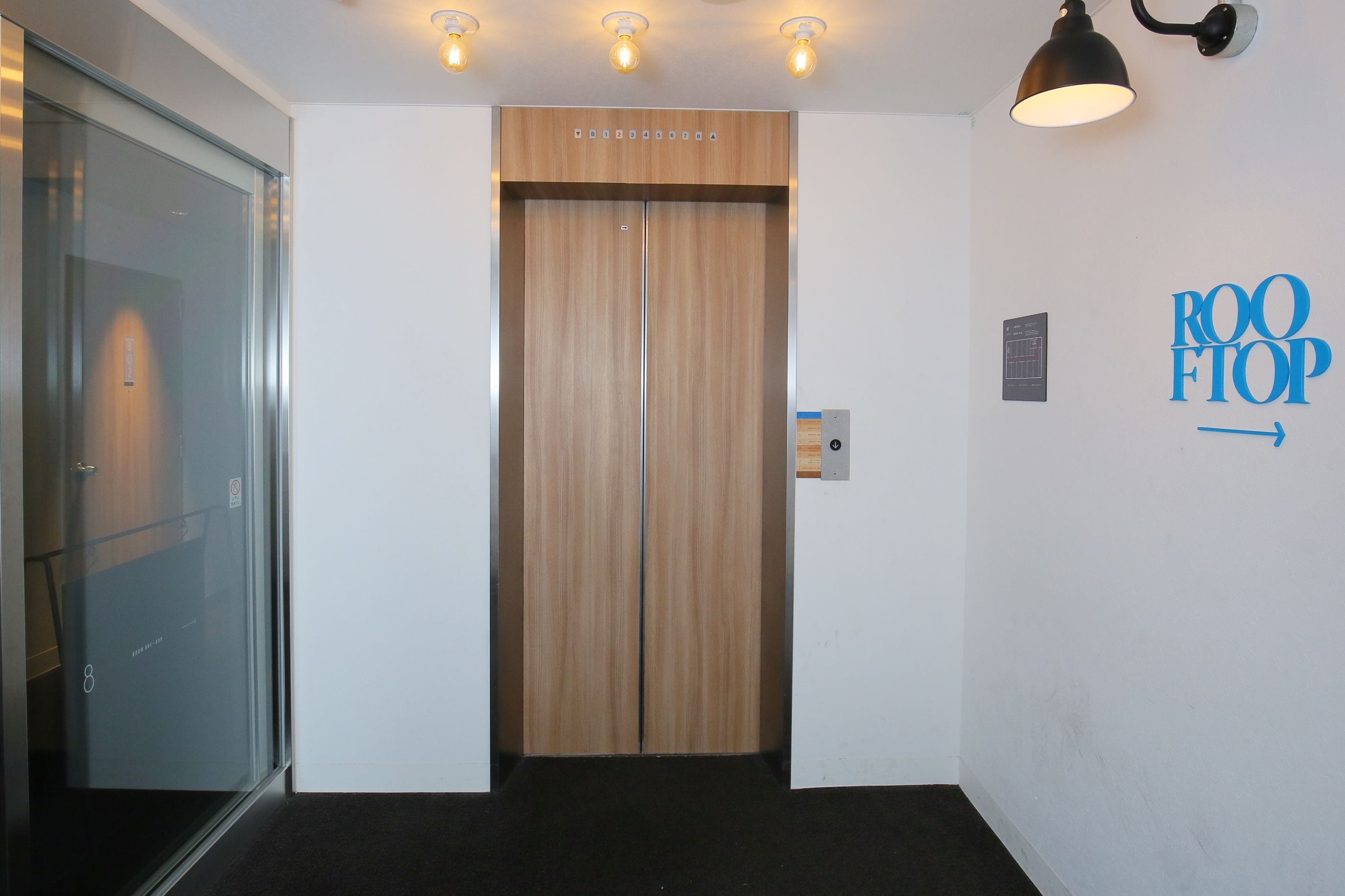 An elevator with a wooden finish and a sign that reads "ROOF TOP" on the wall.
