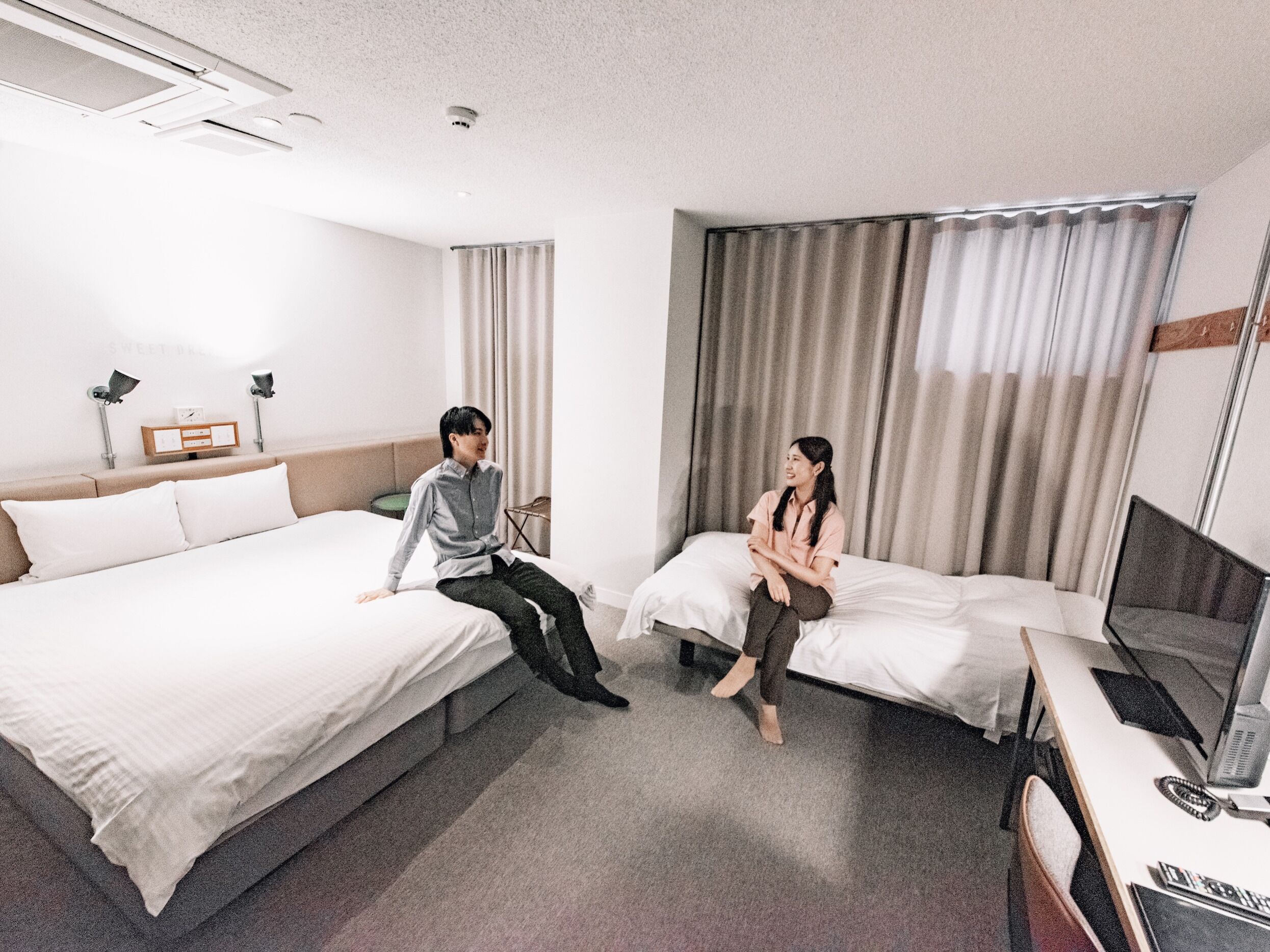 A hotel room with two beds, a desk with a computer, and a TV.