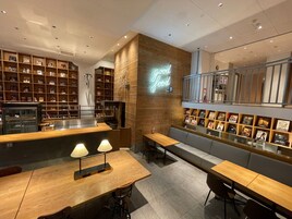 A cozy cafe with wooden shelves, a neon sign, and seating areas.