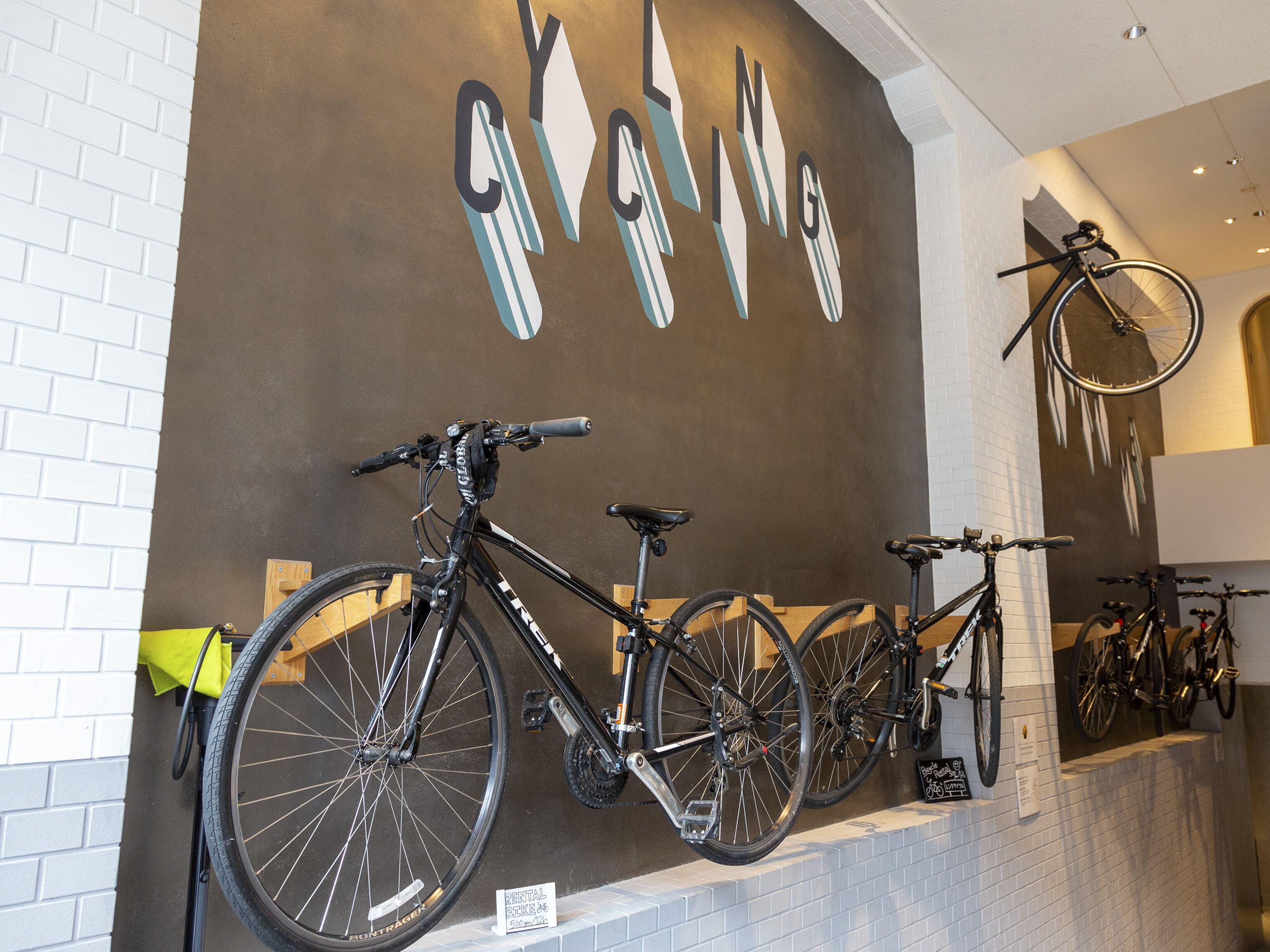 A bike rental station with bicycles mounted on a wall and a sign indicating rental prices.