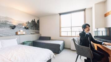 A hotel room with a bed, a desk, a chair, a television, and a window with a city view.