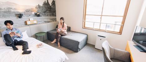 A modern hotel room with a large window, a bed, a sofa, a desk, and a chair.