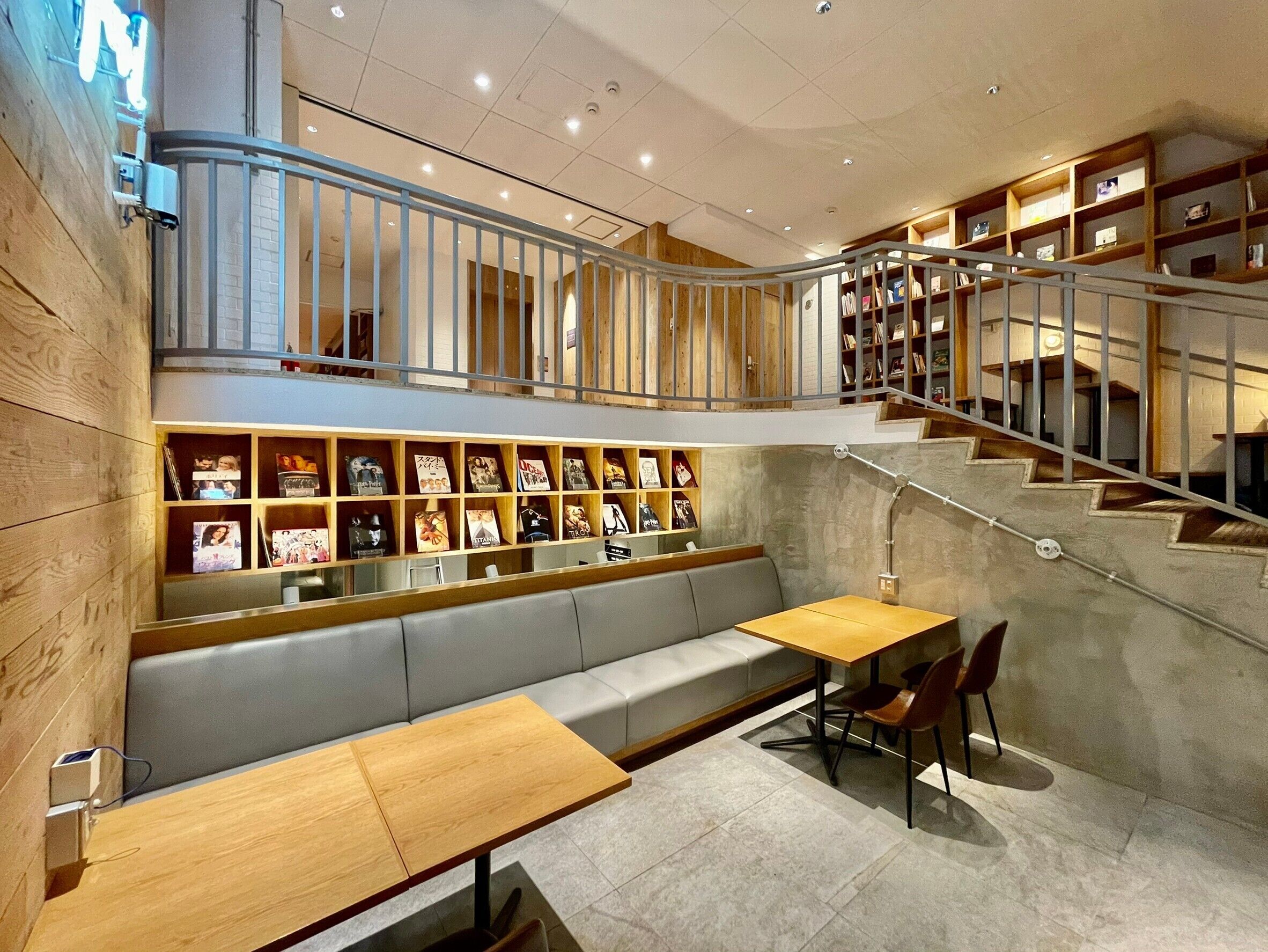 A modern interior with a wooden bench, a table, and a staircase with bookshelves.