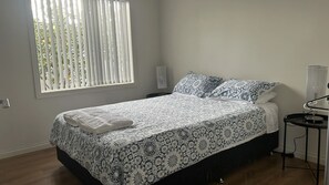 Una camera da letto con un letto, un comodino, una lampada e una finestra con persiane.