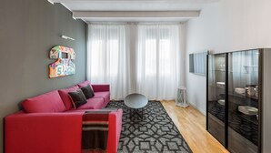 Ein modernes Wohnzimmer mit einem roten Sofa, einem runden Tisch und einer Glastruhe.