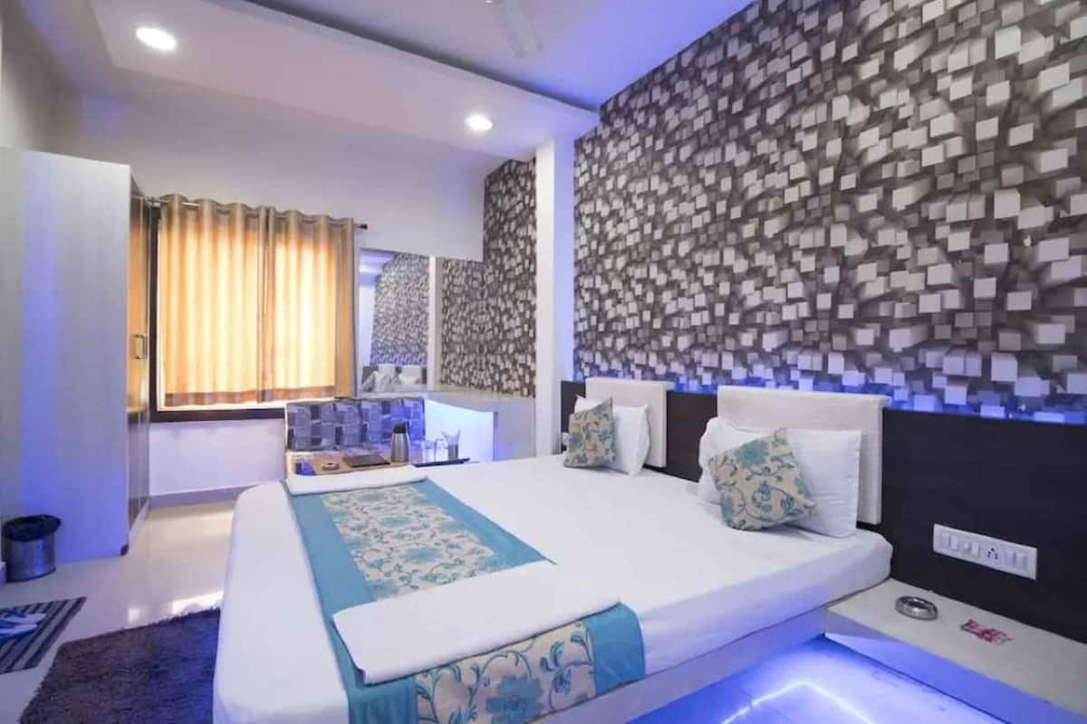 Een moderne hotelkamer met een groot bed, een nachtkastje, een spiegel en een behang met een patroon.
