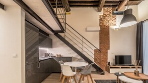 Een moderne keuken met een eethoek, een trap en een woonkamer met televisie en zitplaatsen.