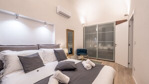 Een moderne slaapkamer met een groot bed, een spiegel, een kledingkast en een airconditioning.