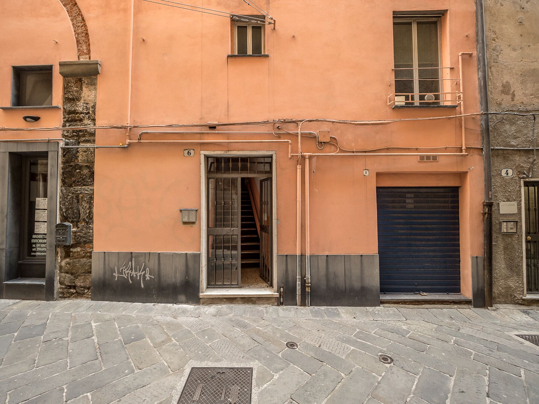 Un edificio con facciata in pietra, cancello in metallo e porta garage blu.