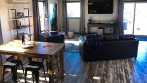 A modern living room with a dining area, a large TV, and a unique light fixture. - Papillon Cellars (Mariposa)