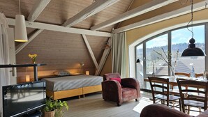 Une pièce confortable avec un lit, une télévision, une table à manger et une grande fenêtre donnant sur l’extérieur.