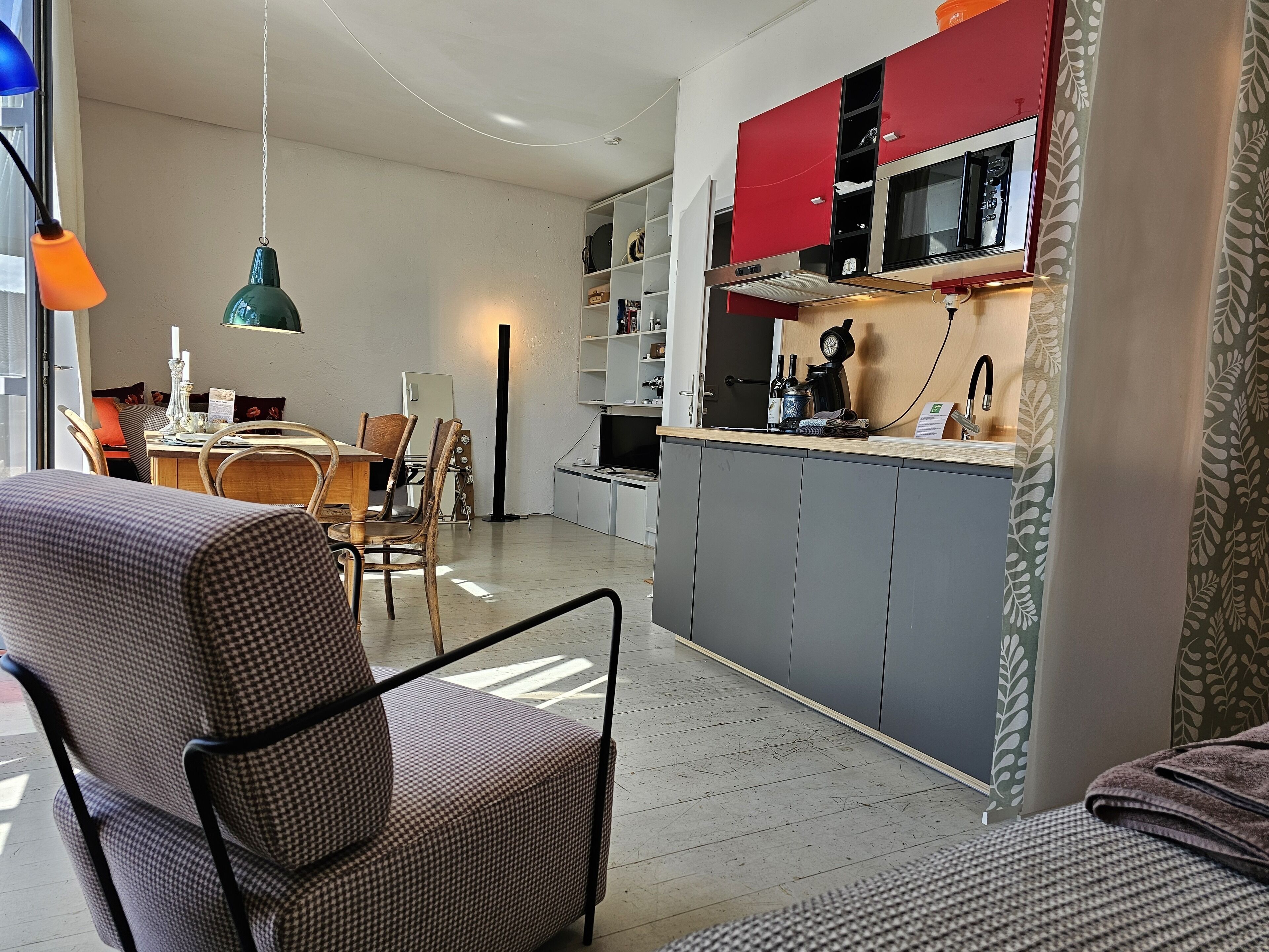 Una cocina moderna con gabinetes grises, una sección superior roja y un microondas integrado.