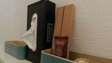 A shelf with a black box labeled 'KOSMETIKTÜCHER FACIAL TISSUES', a brown box labeled 'Argan Son', and a blue container with a white tissue.