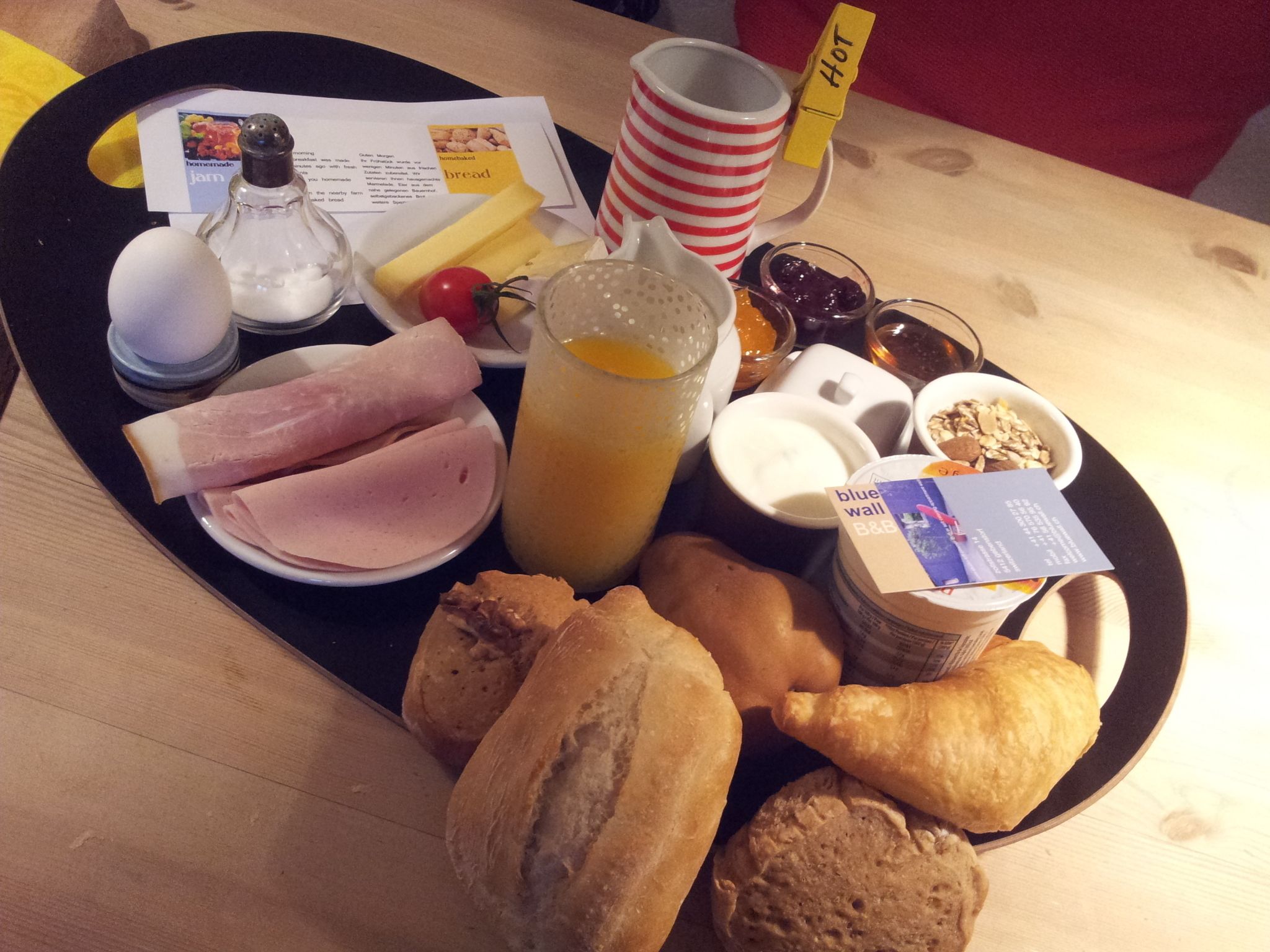 Un plateau de petit-déjeuner avec du jambon, du pain, des œufs, une boisson et un muffin.