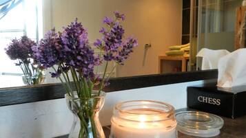Ein Zimmer mit einer Anrichte, auf der eine Vase mit violetten Blumen, eine brennende Kerze und ein Schachspiel stehen.