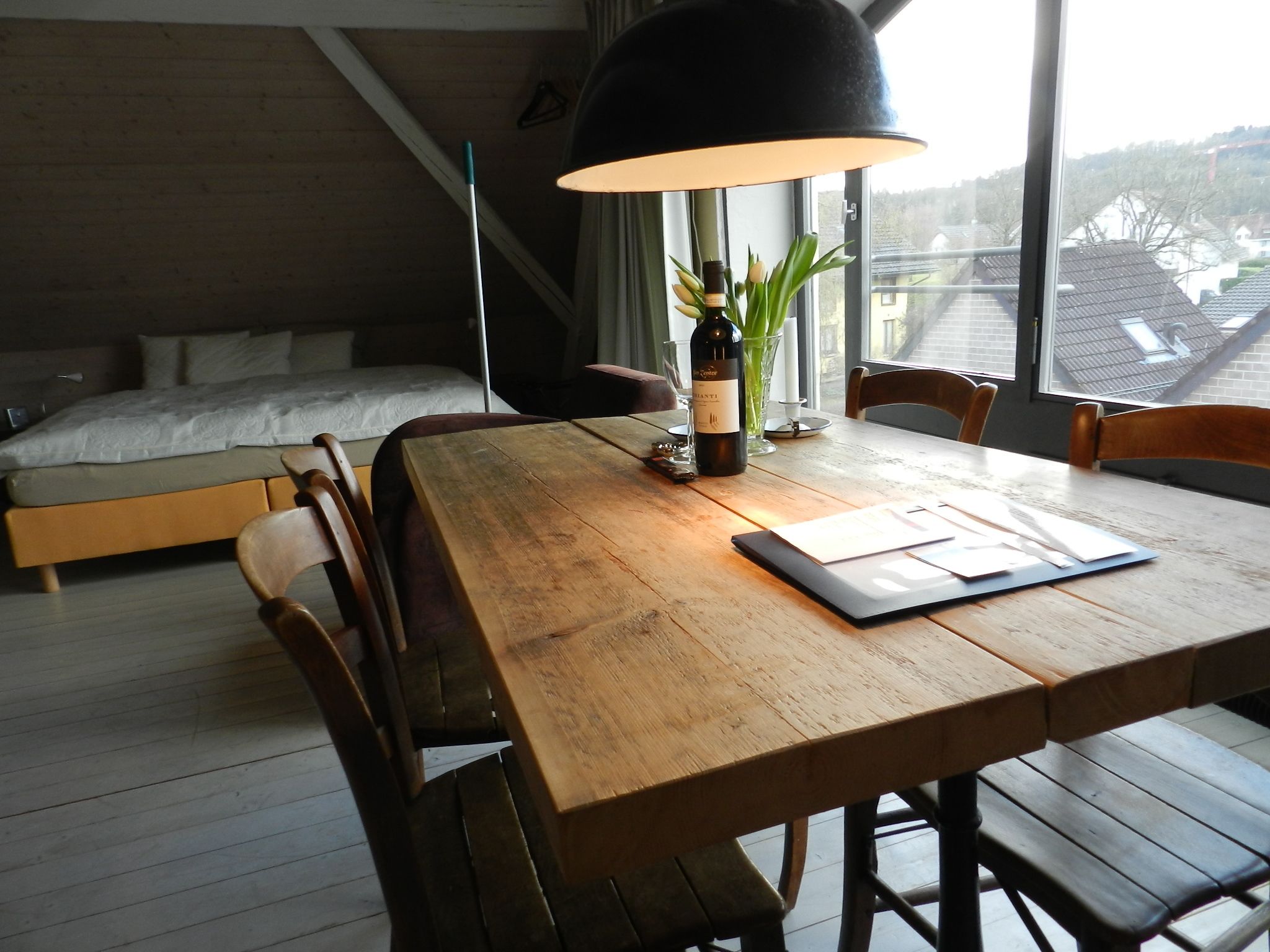 Une chambre moderne avec un lit en bois, une table à manger avec des chaises et une grande fenêtre offrant une vue sur les environs.