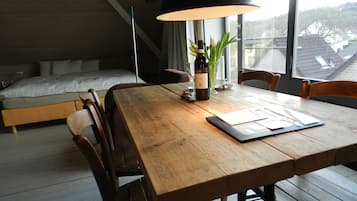 Une chambre moderne avec un lit en bois, une table à manger avec des chaises et une grande fenêtre offrant une vue sur les environs.