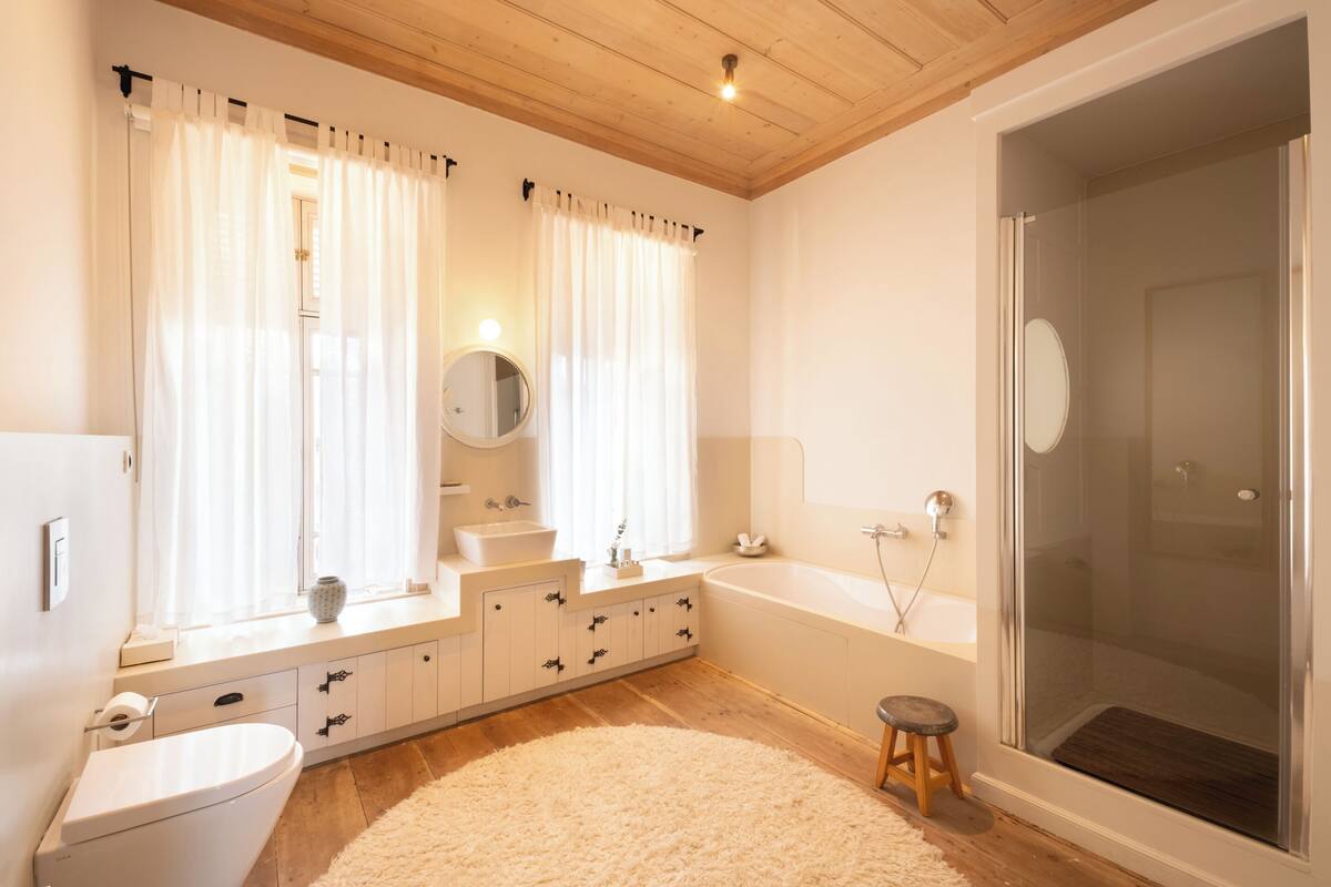 A modern bathroom with a toilet, sink, vanity, bathtub, and shower.