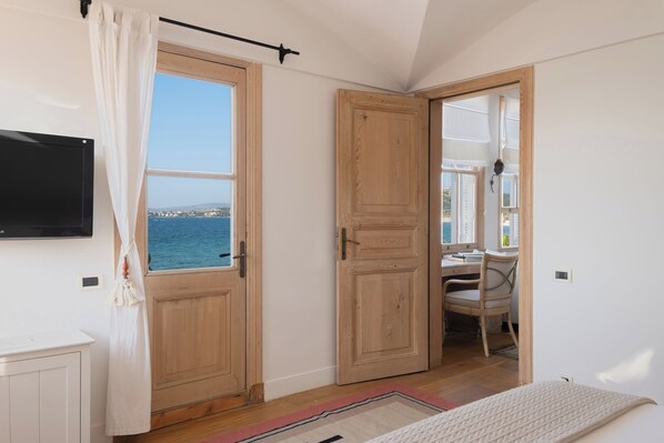 A bedroom with a large window, a desk, and a chair.