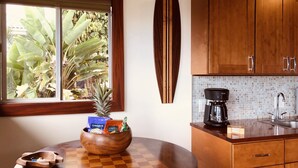 A kitchen with wooden cabinets, a coffee maker, and a surfboard on the wall.