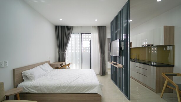 Een moderne hotelkamer met een groot bed, een televisie, een kitchenette en uitzicht op de stad.