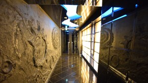 A corridor with a polished floor, stone walls, and a modern light fixture. - Mell-Theater 1102 (Osaka)