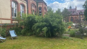 A courtyard with a brick building, a grassy area, and a blue-striped chair.