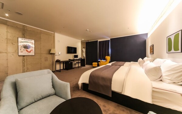 Una habitación de hotel con una cama, un escritorio, una silla y un sofá.
