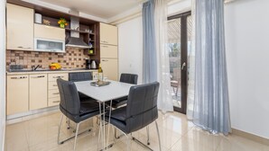 Una cocina moderna con comedor, que incluye una mesa blanca, sillas negras y un salpicadero de azulejos.