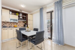 Una cocina moderna con comedor, que incluye una mesa blanca, sillas negras y un salpicadero de azulejos.