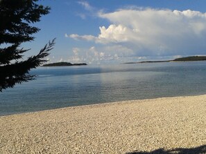 A pebble beach with a calm sea and distant islands. - Dany Apartments (Fazana)