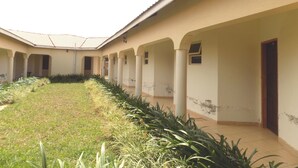 A building with a covered courtyard, columns, and a tiled roof. - Plain Springs Hotel (Kumi)