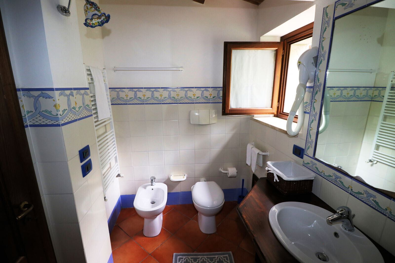 Ein kleines Badezimmer mit integriertem Bidet, Toilette, Waschbecken und einem Spiegel mit Zierrahmen.