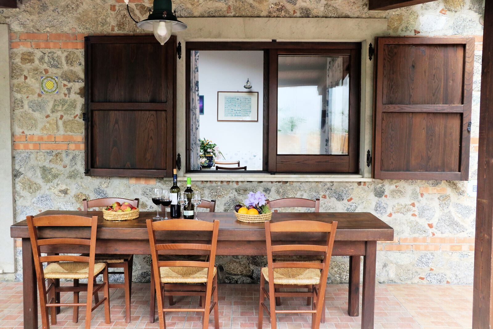 Un coin repas au style rustique, avec un mur en pierre, des meubles en bois et une fenêtre donnant sur un jardin.