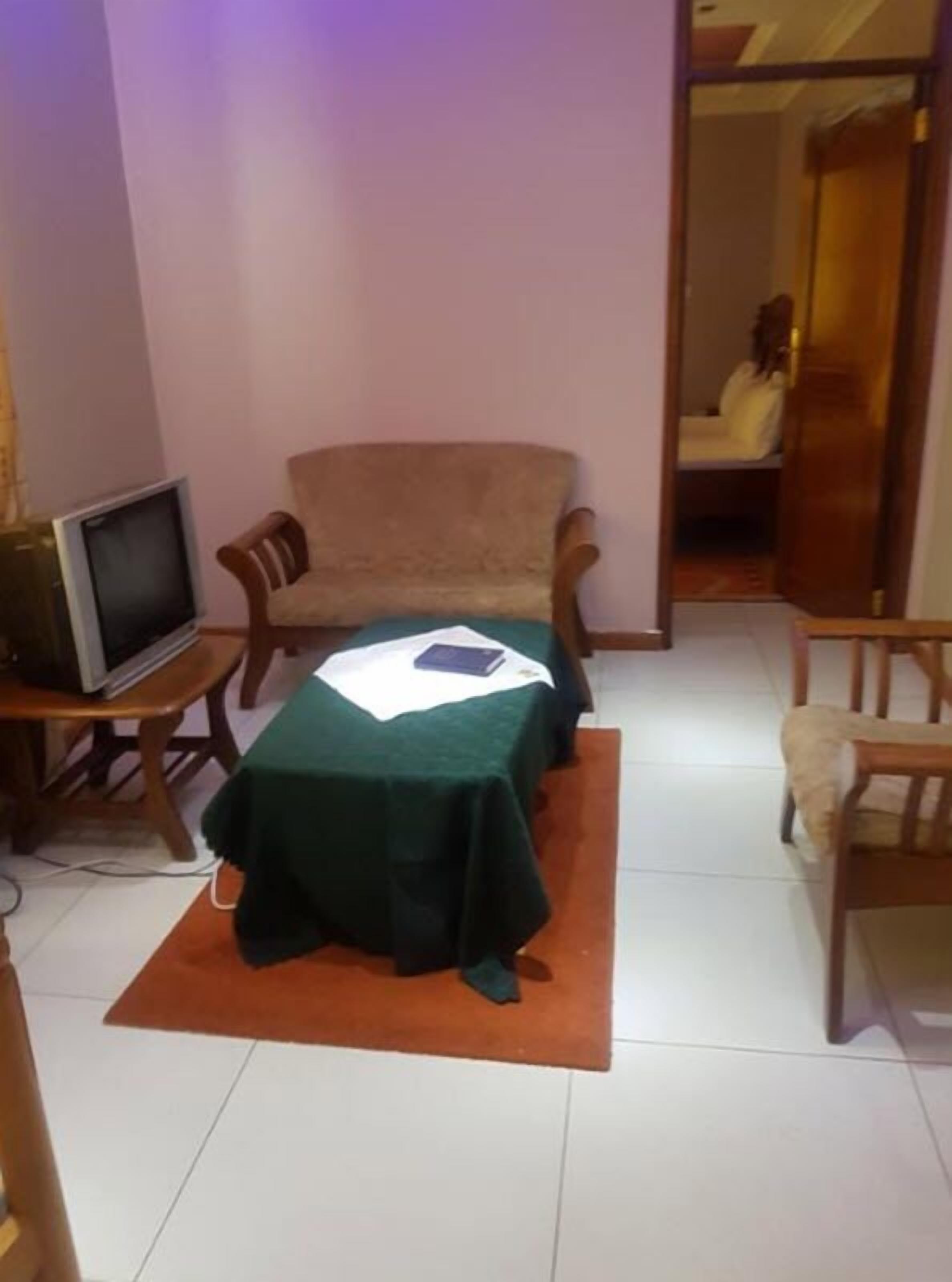 A small room with a green table, a chair, a television, and a door leading to another room.