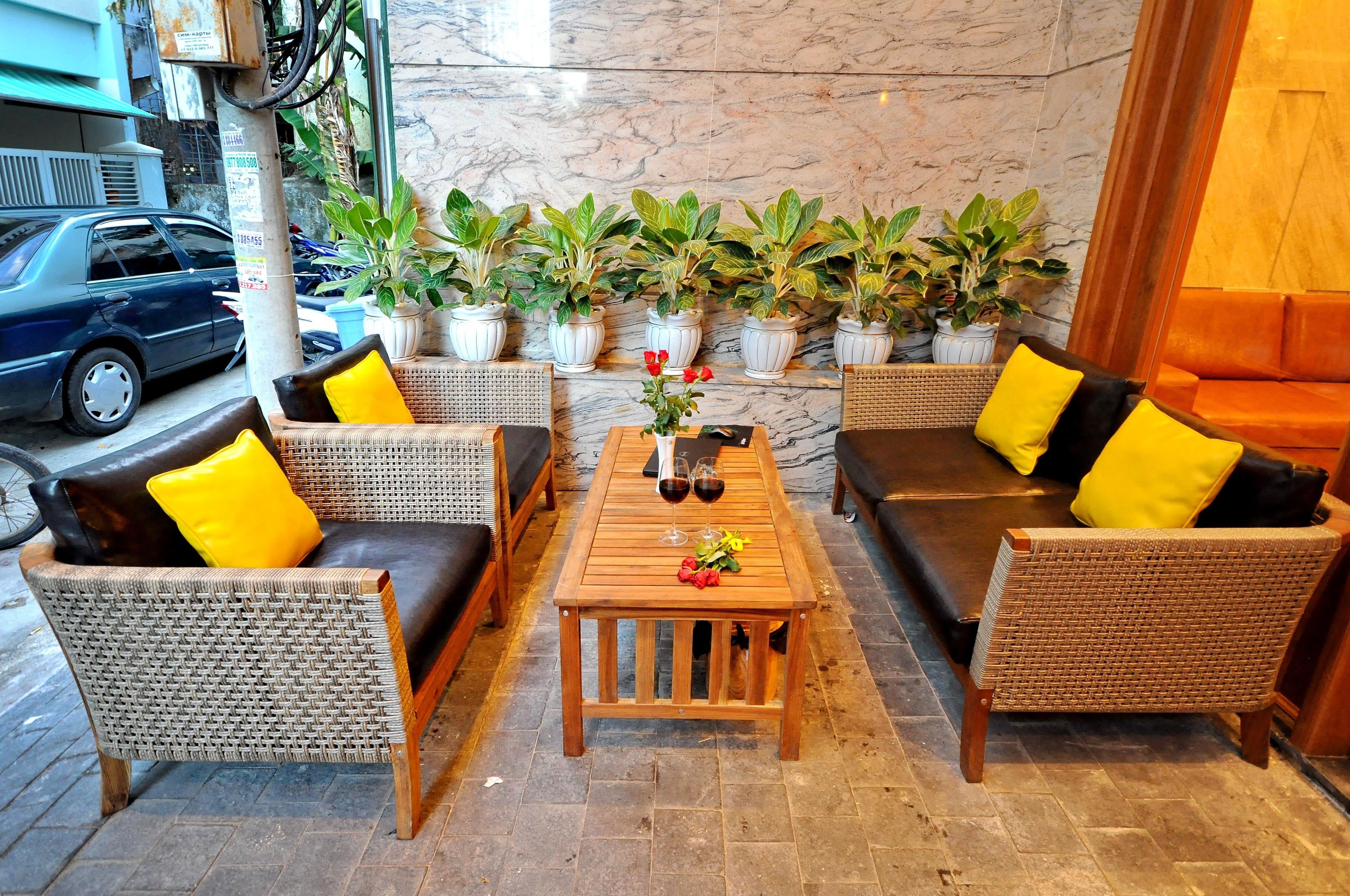 A seating area with wicker furniture, a wooden table, and potted plants.