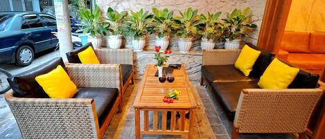 A seating area with wicker furniture, a wooden table, and potted plants.