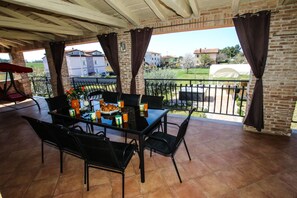 A covered patio with a table set for two, featuring a glass top and black metal chairs. - Apartment Tina with Hot Tub (Porec)