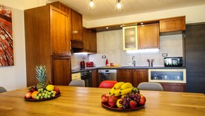 Une cuisine moderne avec des meubles en bois, une table à manger ornée de fruits et un four à micro-ondes.